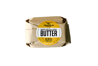 Ploughgate Creamery cultured butter in 8 oz block, wrapped in gold foil with elegant label, displayed on a wooden board with bread and knife